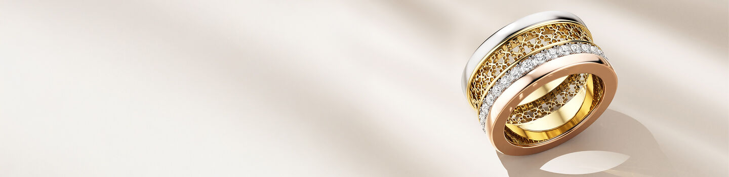 Birks Dare to Dream tri-gold and diamond ring on a beige background.