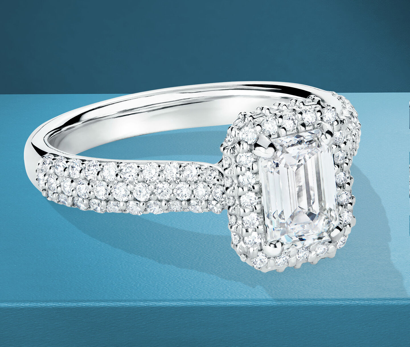 Birks Square Phillips emerald-cut diamond engagement ring on a blue background.