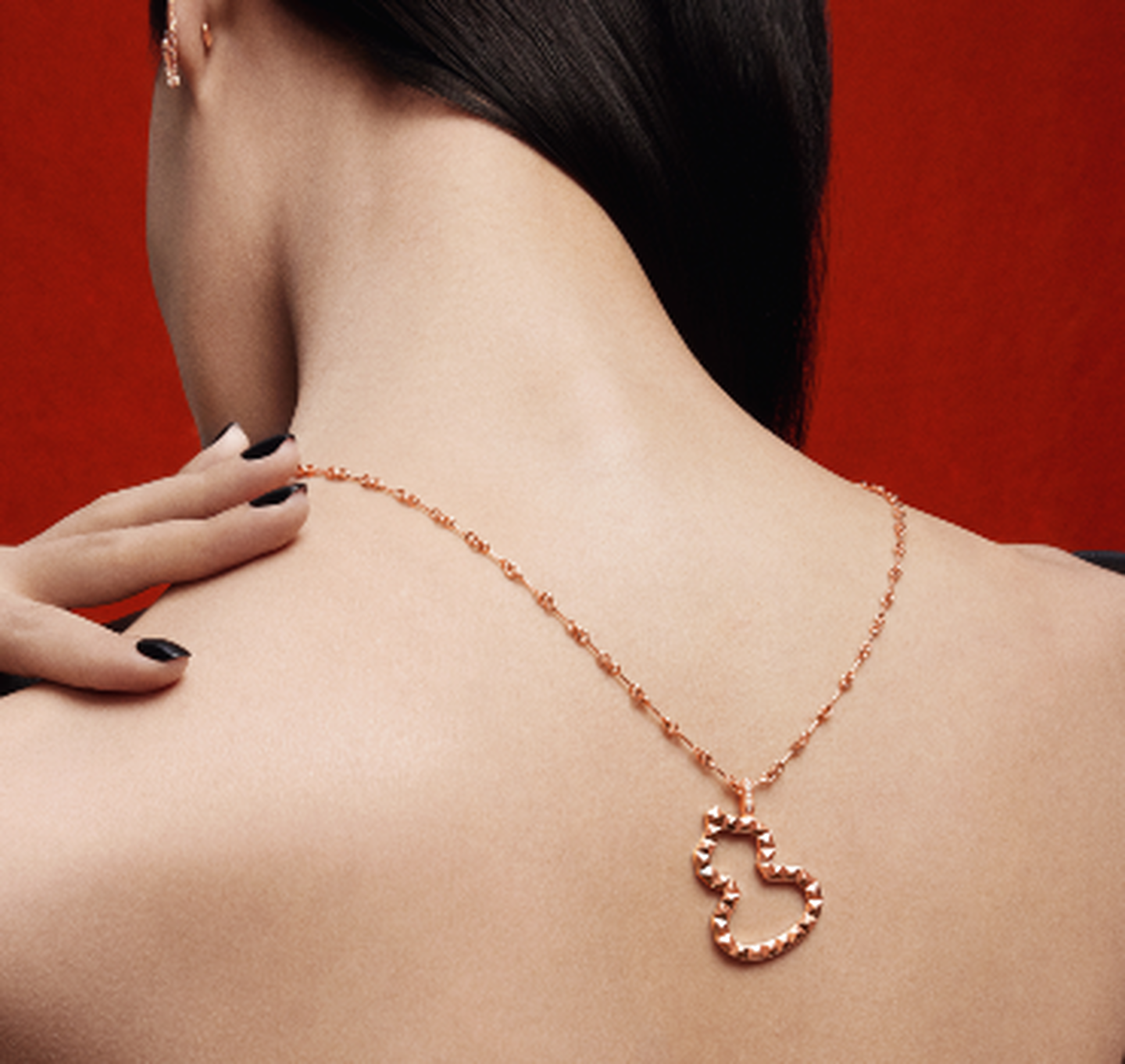 A Qeelin Wulu rose gold and diamond pendant on a woman's back.