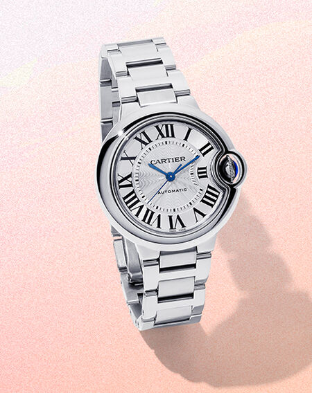 Montre Ballon Bleu de Cartier sur un fond rose et beige.