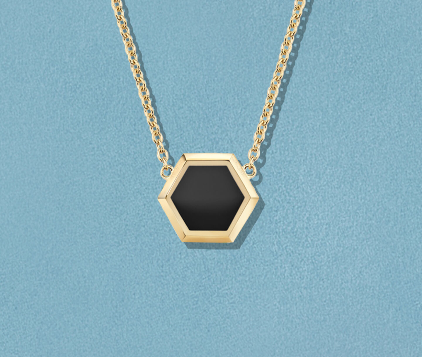 Collier Birks Bee Chic en or jaune et onyx sur un fond bleu.