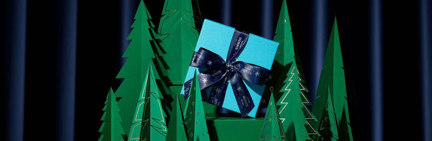 A wrapped present between green paper trees.
