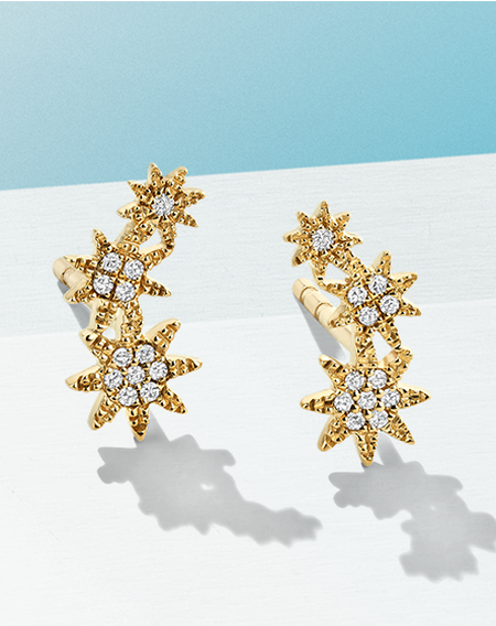 Shy Creation diamond and yellow gold earrings on a blue background.