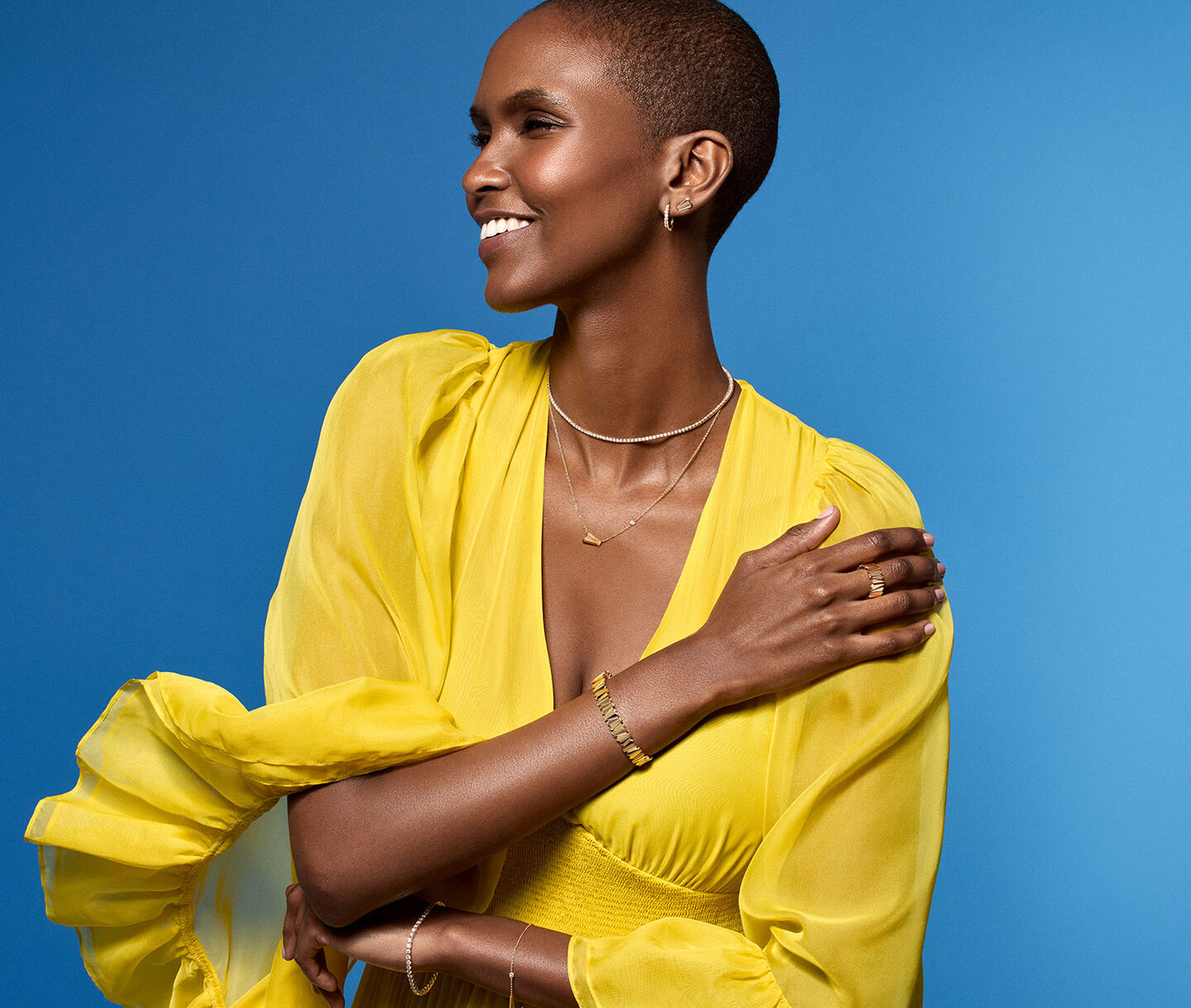 Une femme porte les bijoux en or jaune Birks sur un fond bleu.