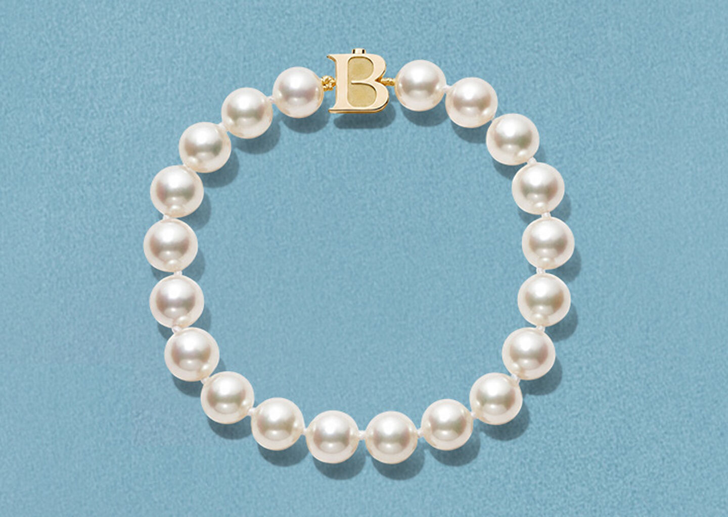 Bracelets Birks Perles Akoya sur un fond bleu.