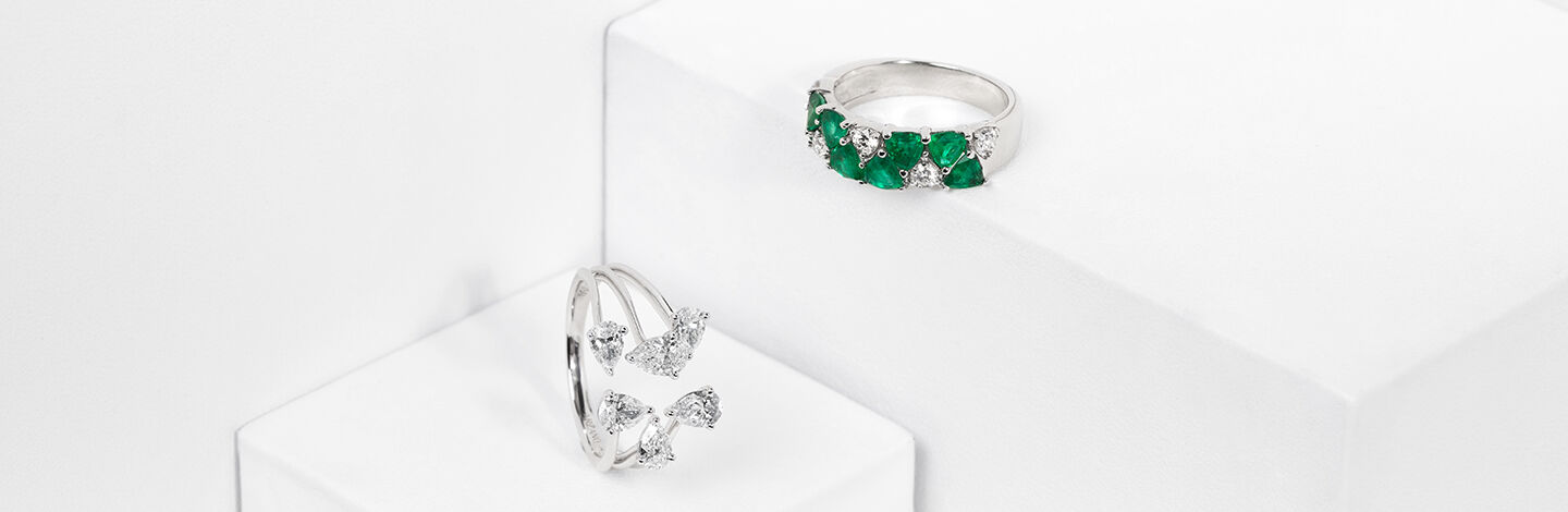 A Maison Birks Salon emerald ring sits next to a diamond pronged ring