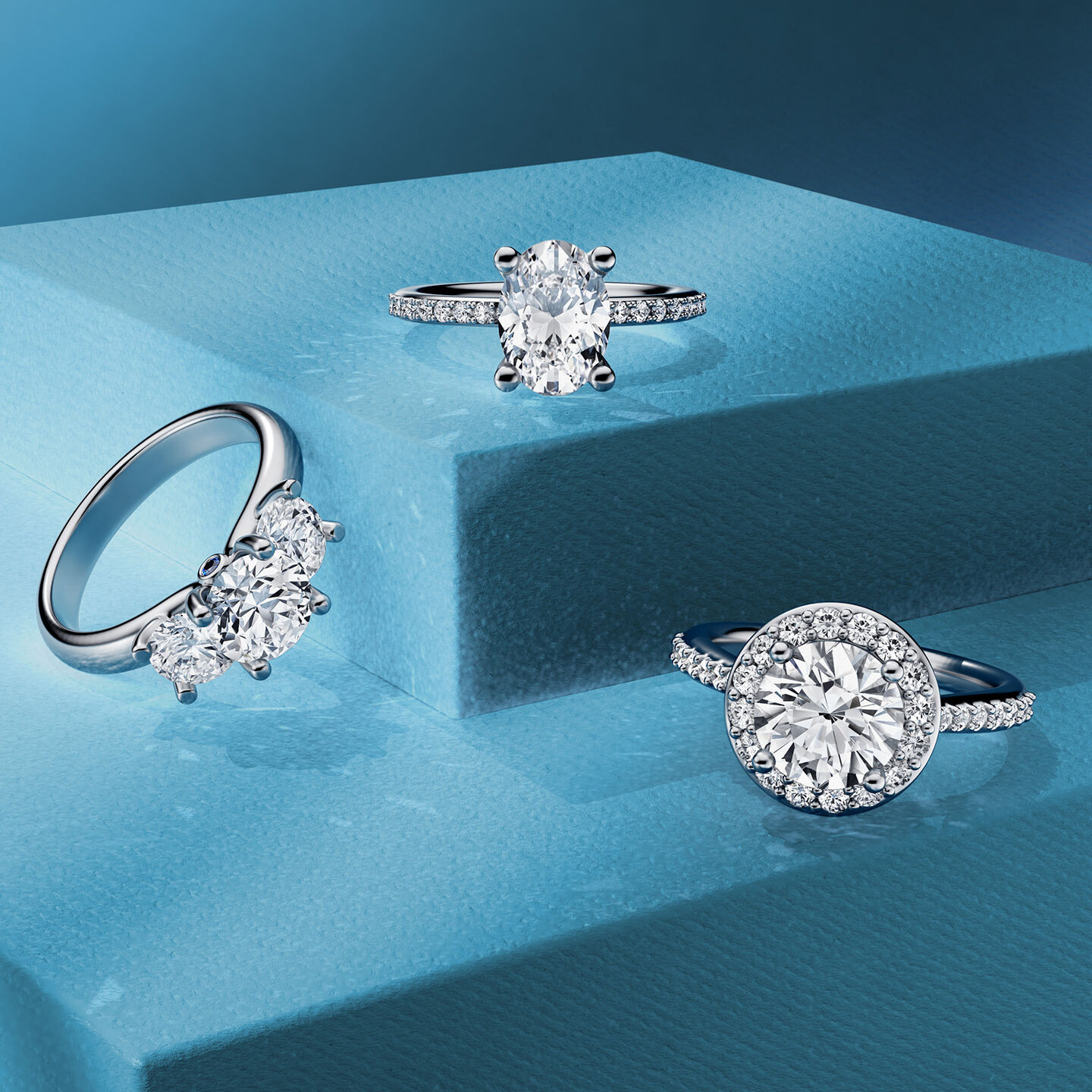 Three Birks diamond engagement rings on a blue background.