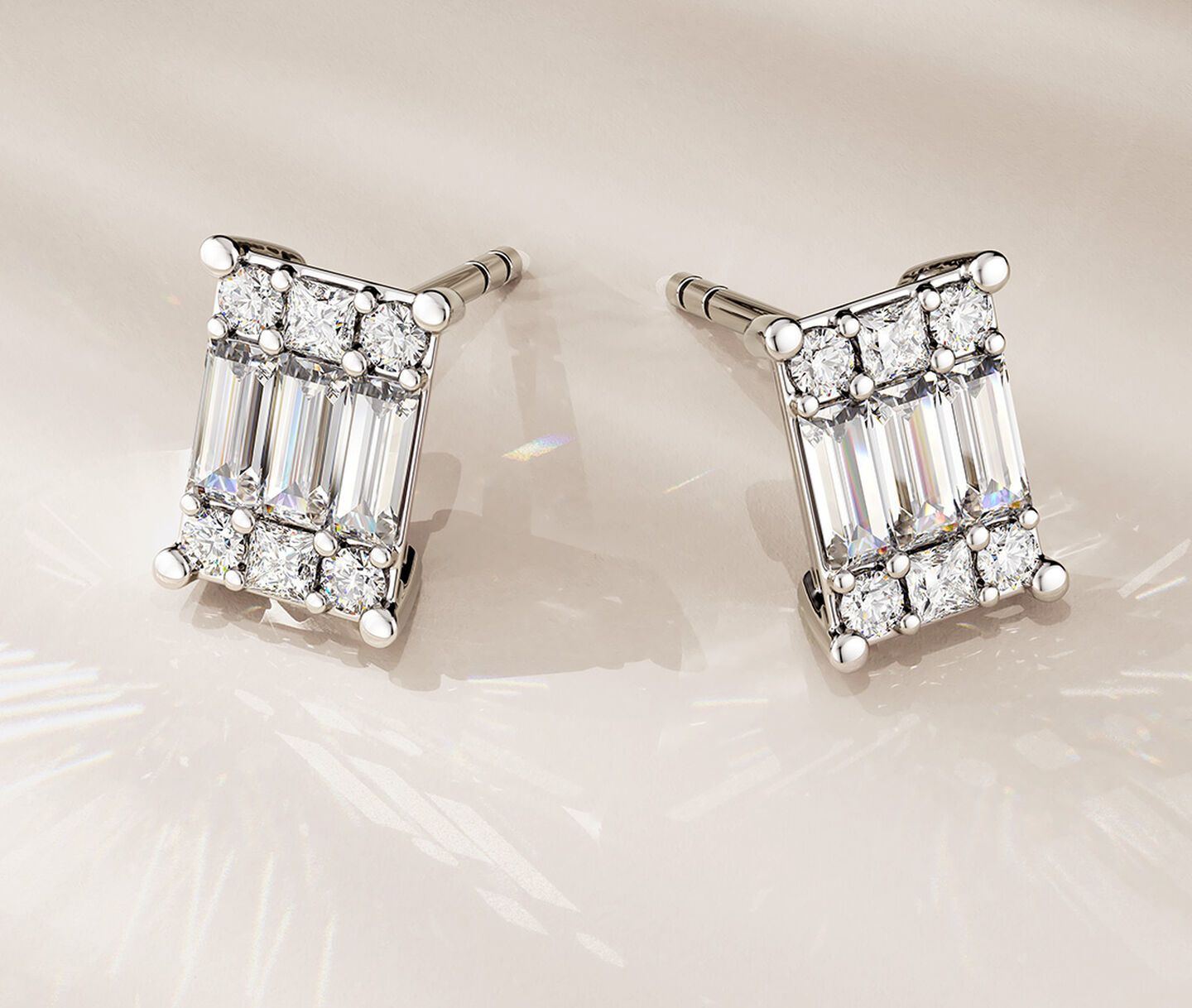 Birks Essentials diamond earrings on a beige background.