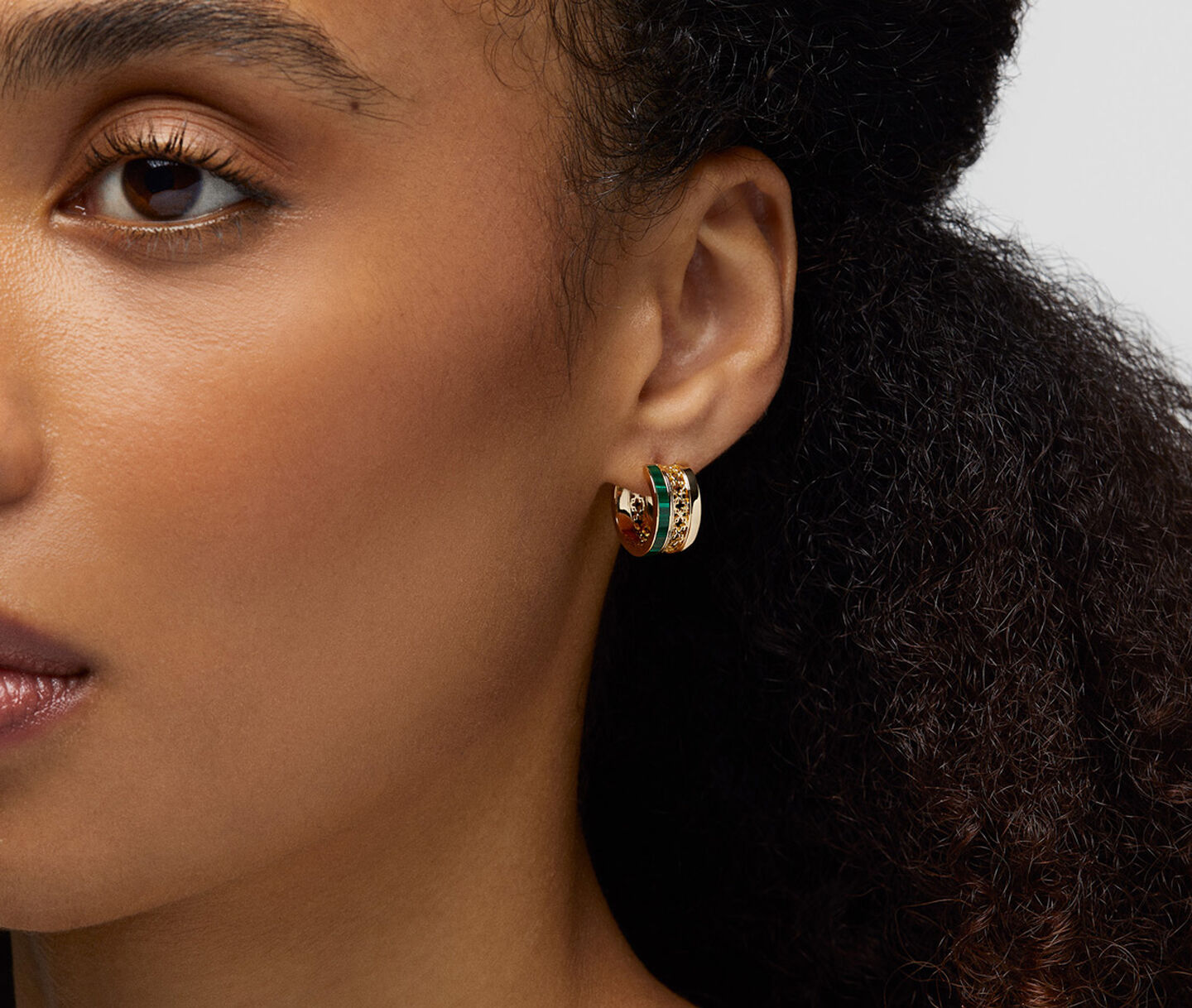 Une femme porte les boucles d'oreilles avec malachite Birks Dare to Dream.