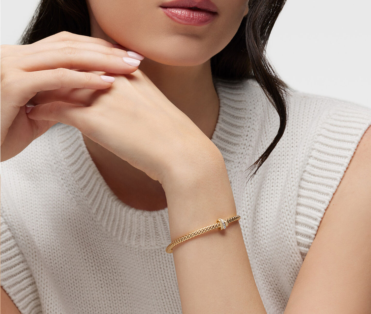Une femme porte un bracelet FOPE en or.