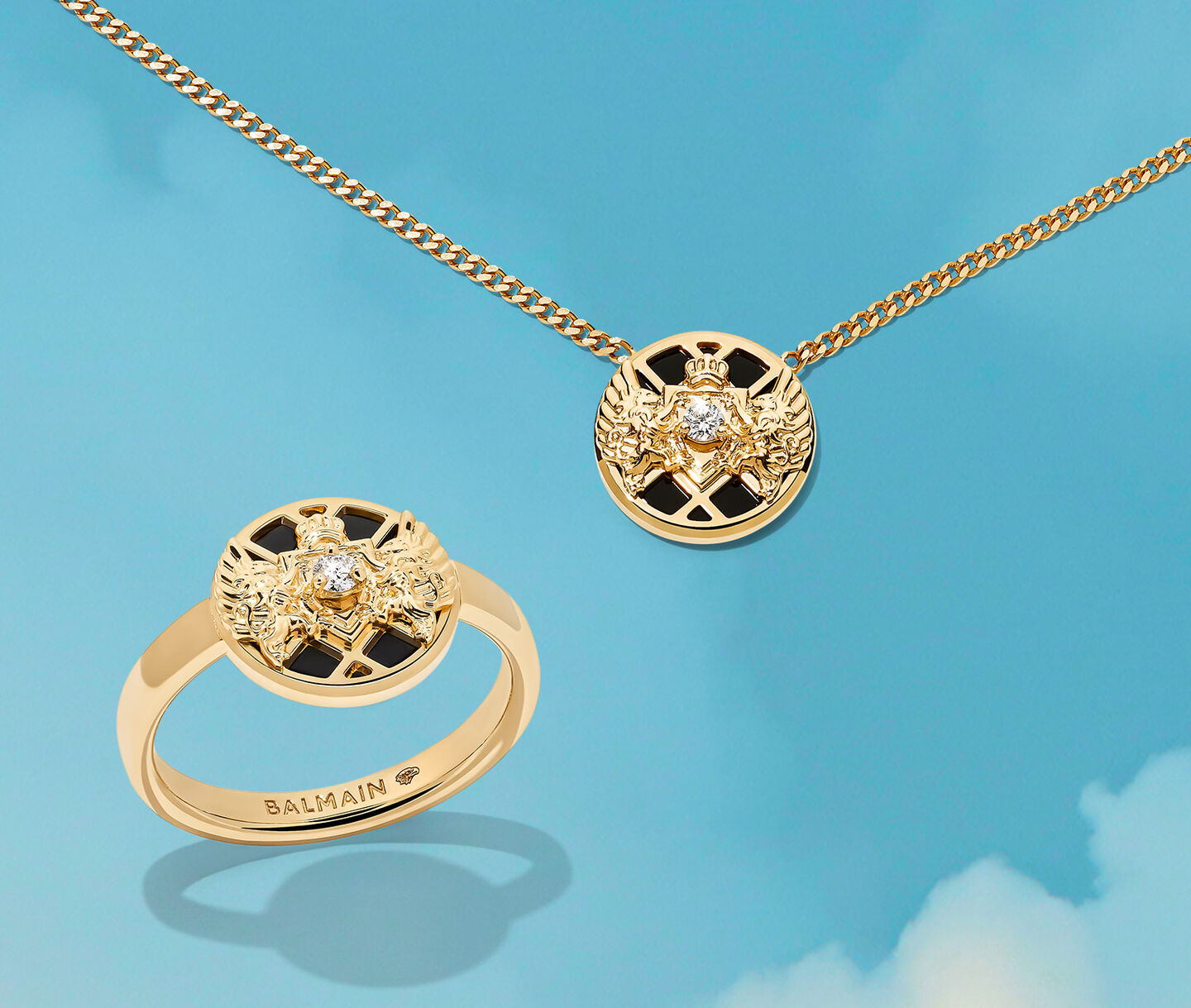 Bague et pendentif Emblem en or de Balmain sur un fond bleu