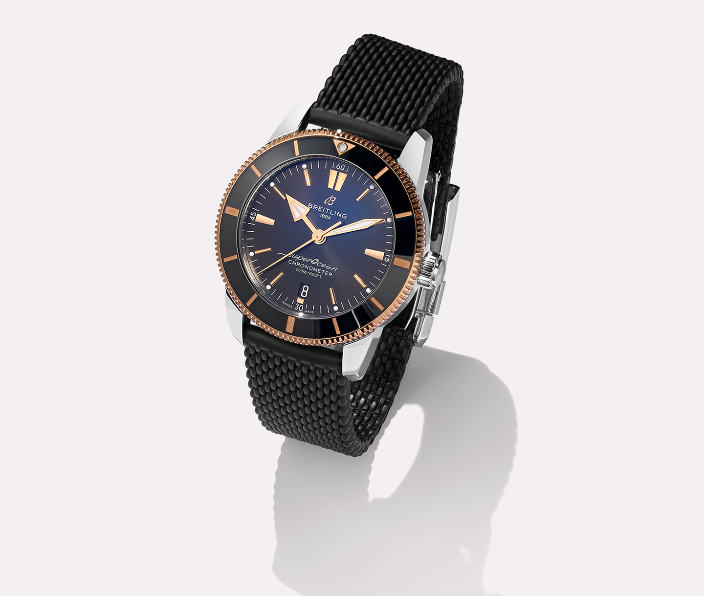 Breitling 18kt Superocean heritage watch with a rubber bracelet on a beige background.