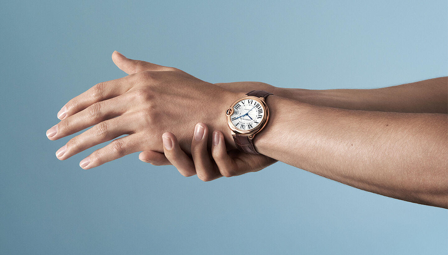 A man wearing a Ballon Bleu de Cartier watch on a blue background.