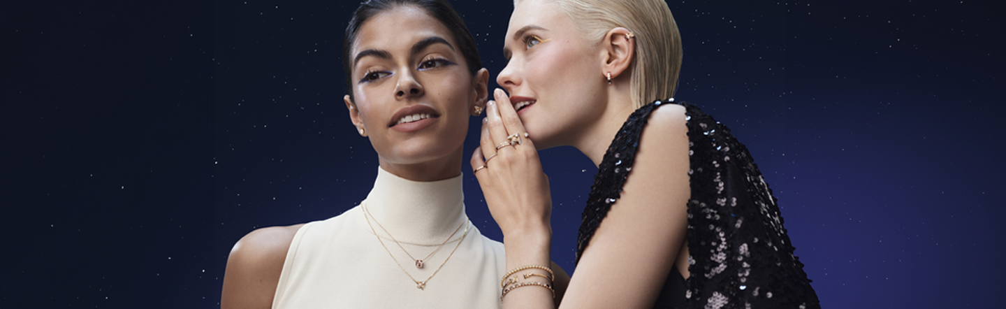 Two people wearing elegant Chaumet jewelry against a starry night background.