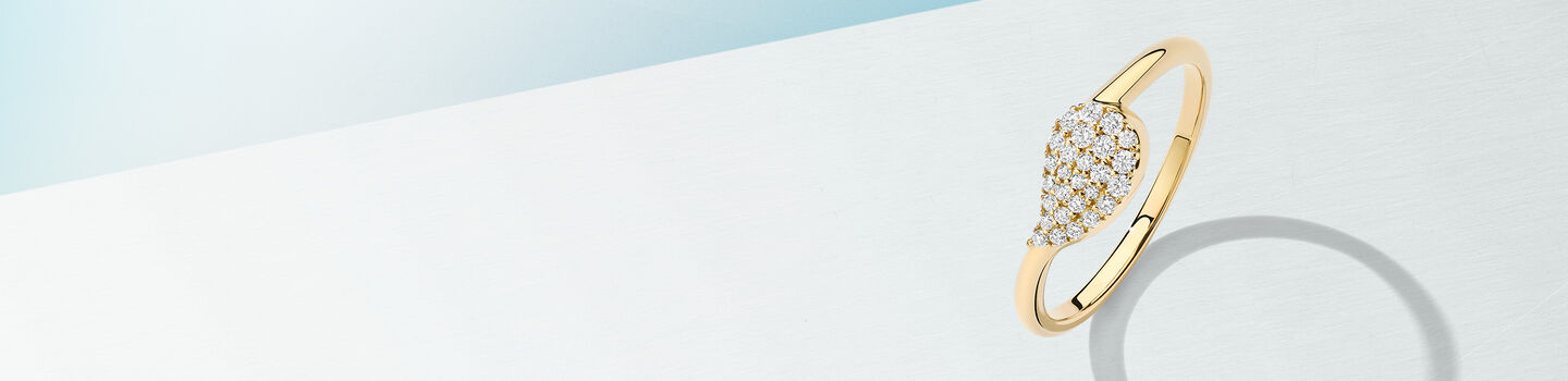 Birks Petale yellow gold and diamond ring on a blue background.