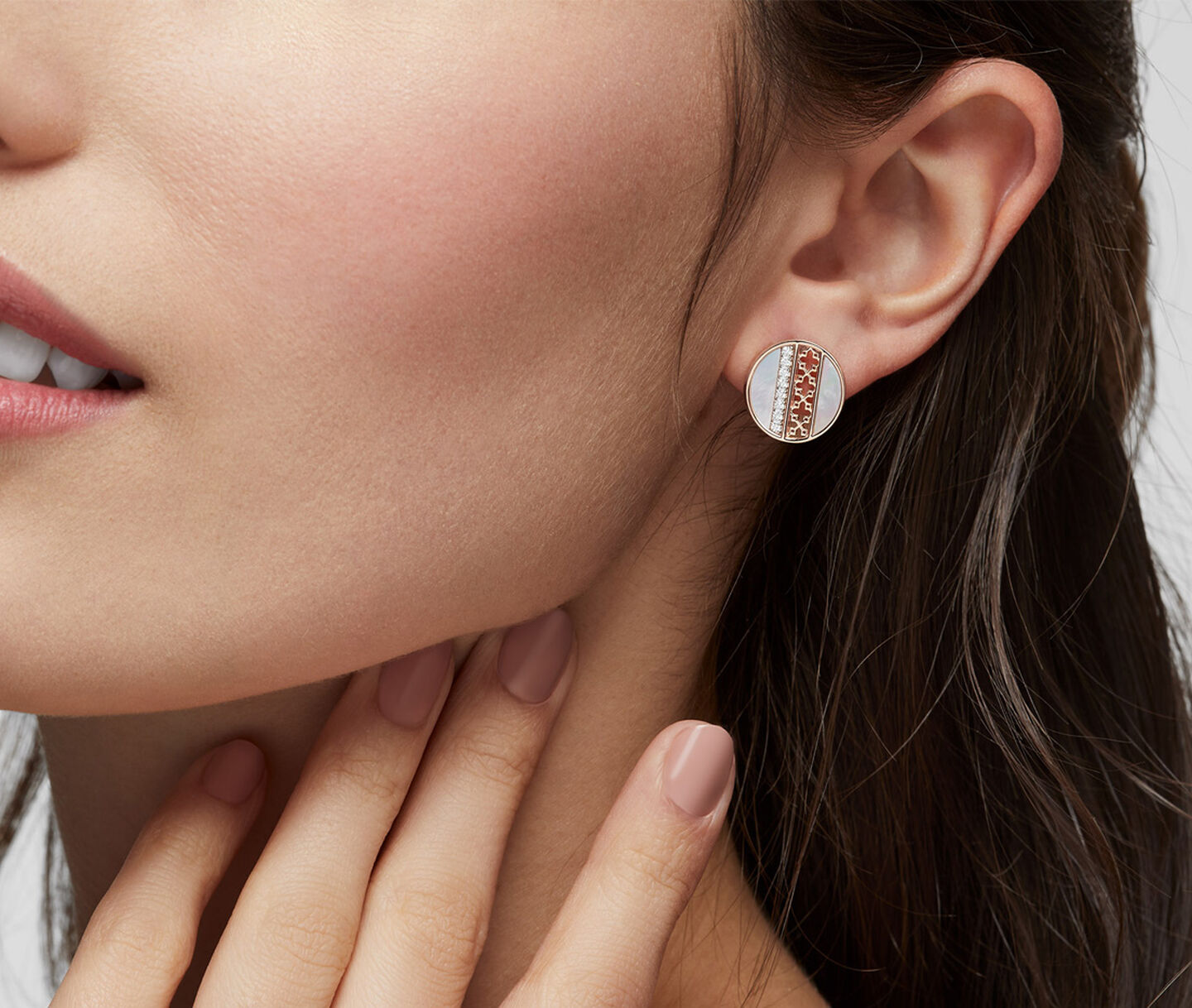 A woman wearing Birks Dare to Dream rose gold and mother-of-pearl stud earrings.
