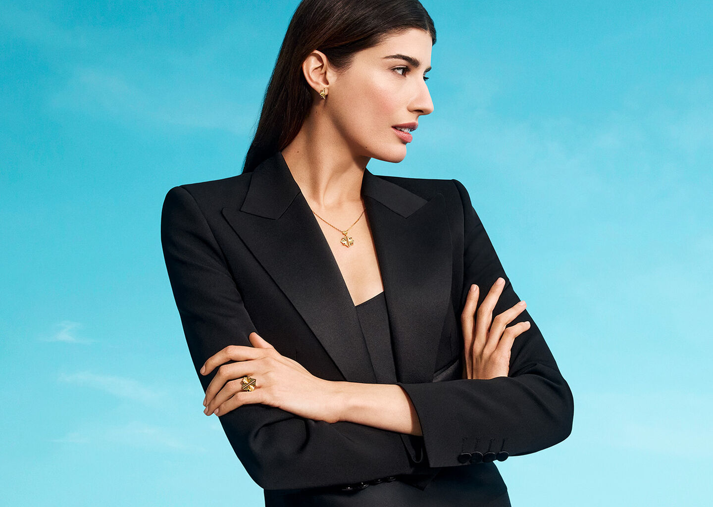 A woman wearing Birks Muse jewellery on a blue background.