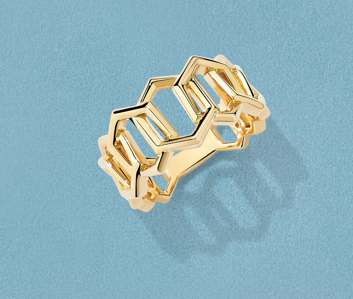 Bague Birks Bee Chic en or jaune sur un fond bleu.