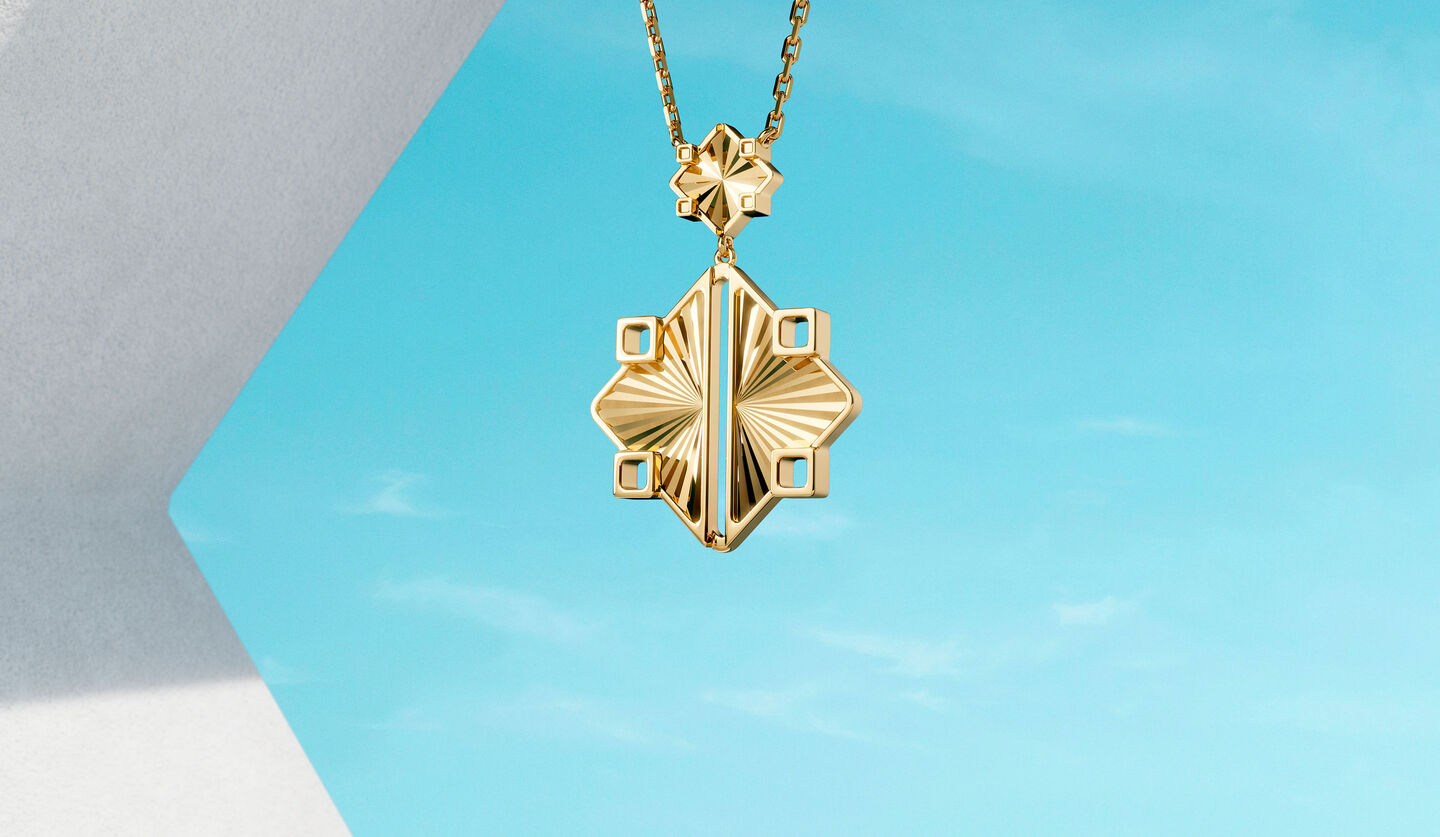 Birks Muse yellow gold drop necklace on a blue background.