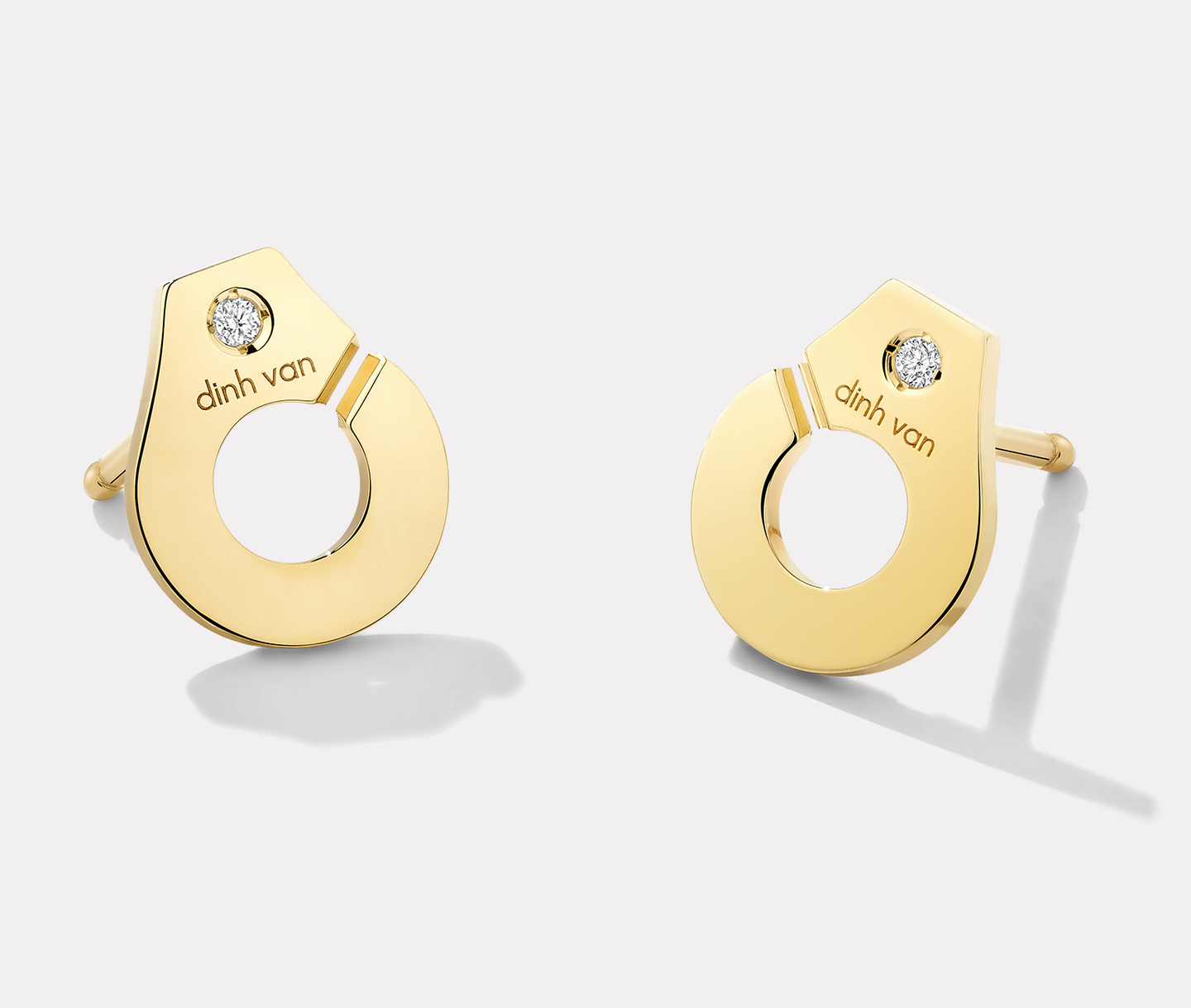 dinh van Menottes R7.5 Yellow Gold and Diamond Stud Earrings on a cream background.