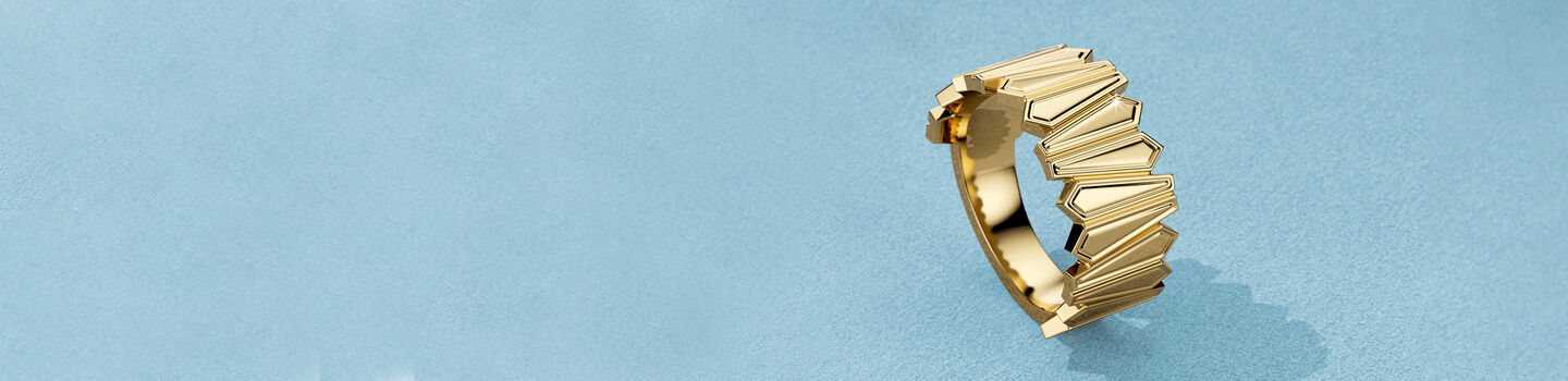 Bague Birks Beekeeper en or jaune sur fond bleu.