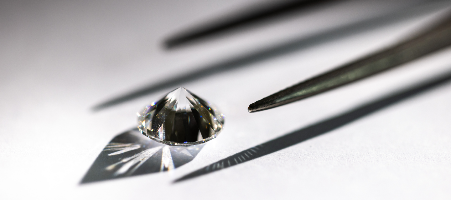 A raw diamond sits on a white table