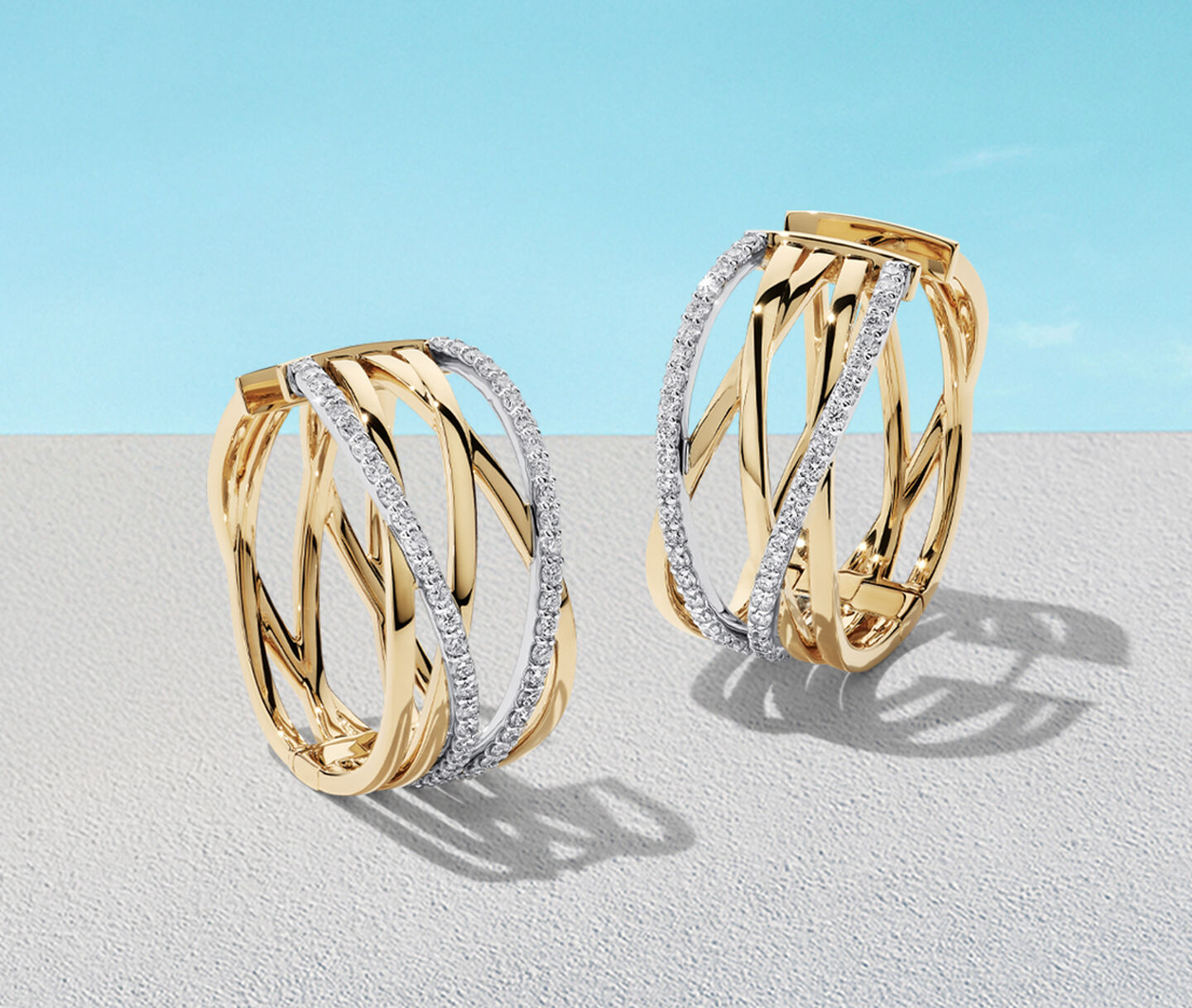 Birks Rosee du Matin gold hoop earrings on a blue background.