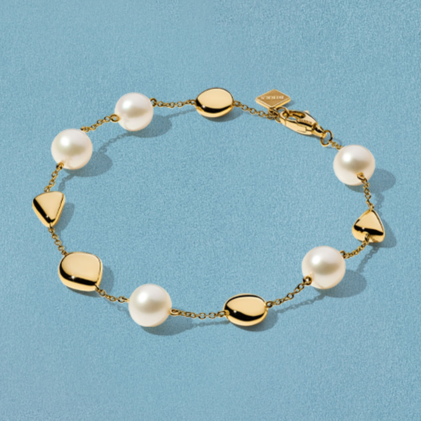 Bracelet Birks Pebble en or jaune sur un fond bleu.