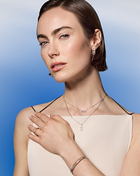 A woman wearing Messika diamond jewellery on a blue background.