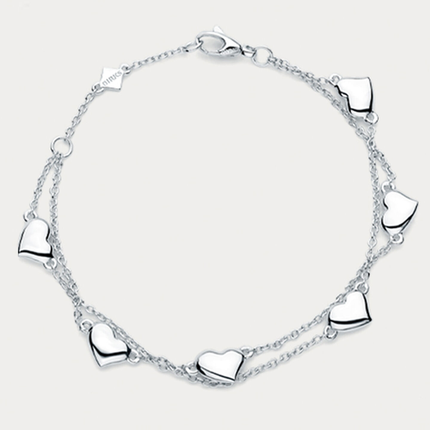 Birks heart bracelet in silver for babies on a beige background.