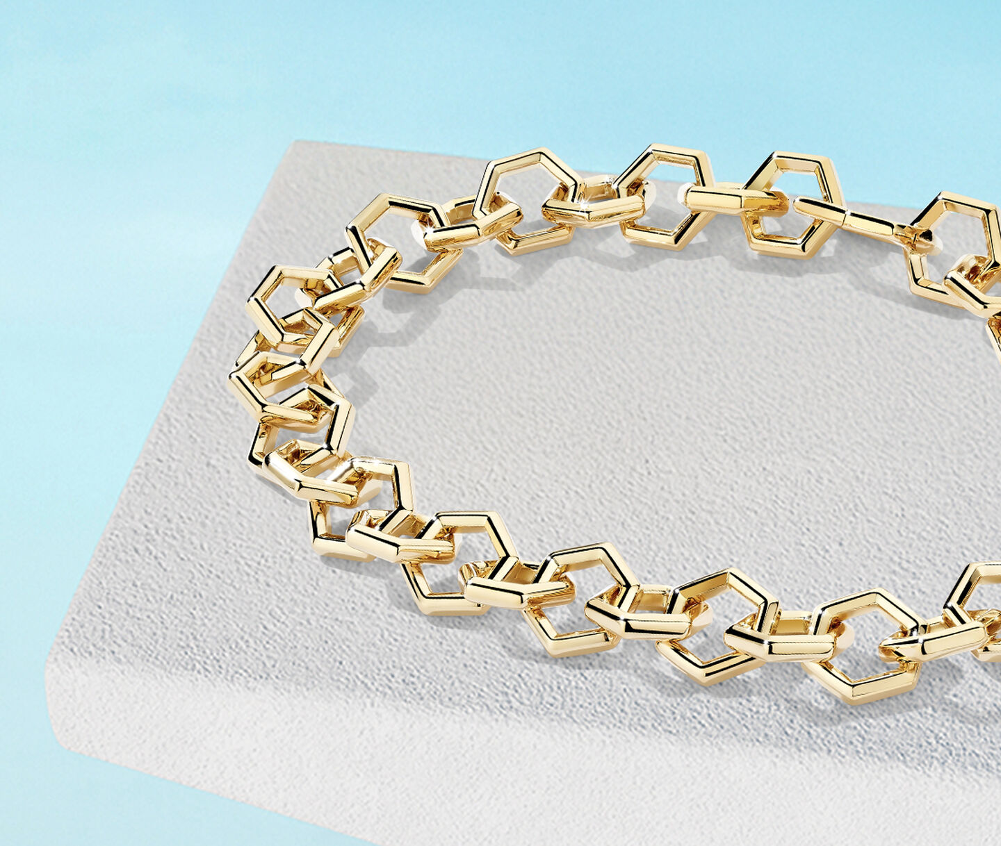 Birks Bee Chic yellow gold bracelet on a blue background.