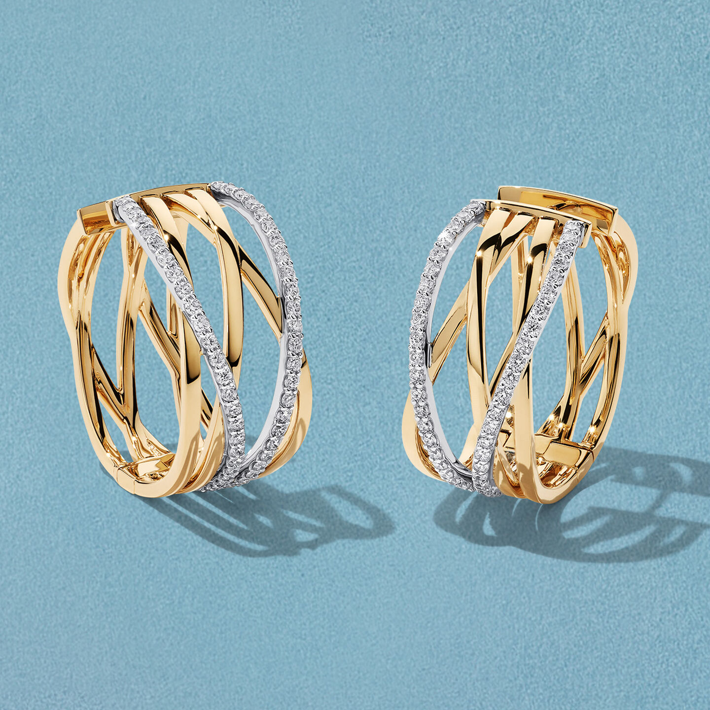 Boucles d'oreilles Birks Rosee du Matin en or jaune avec diamants sur un fond bleu.