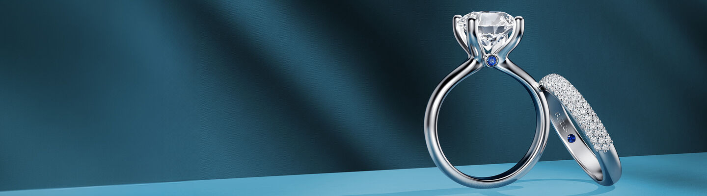 Birks Blue engagement ring and wedding band on a blue background.