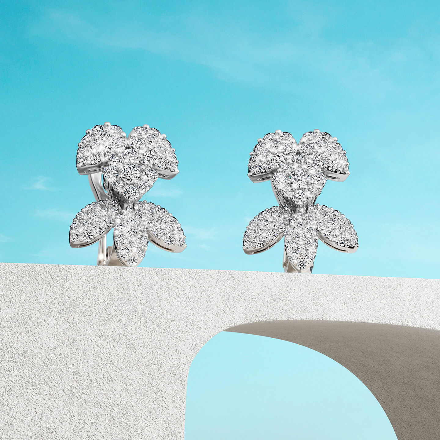 Birks Snow Angel earrings on a blue background.