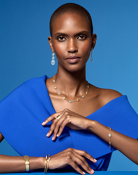 A woman wearing Marco Bicego jewellery on a blue background.