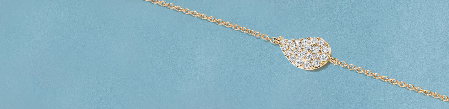 Birks P&eacute;tale diamond yellow gold necklace on a blue background.