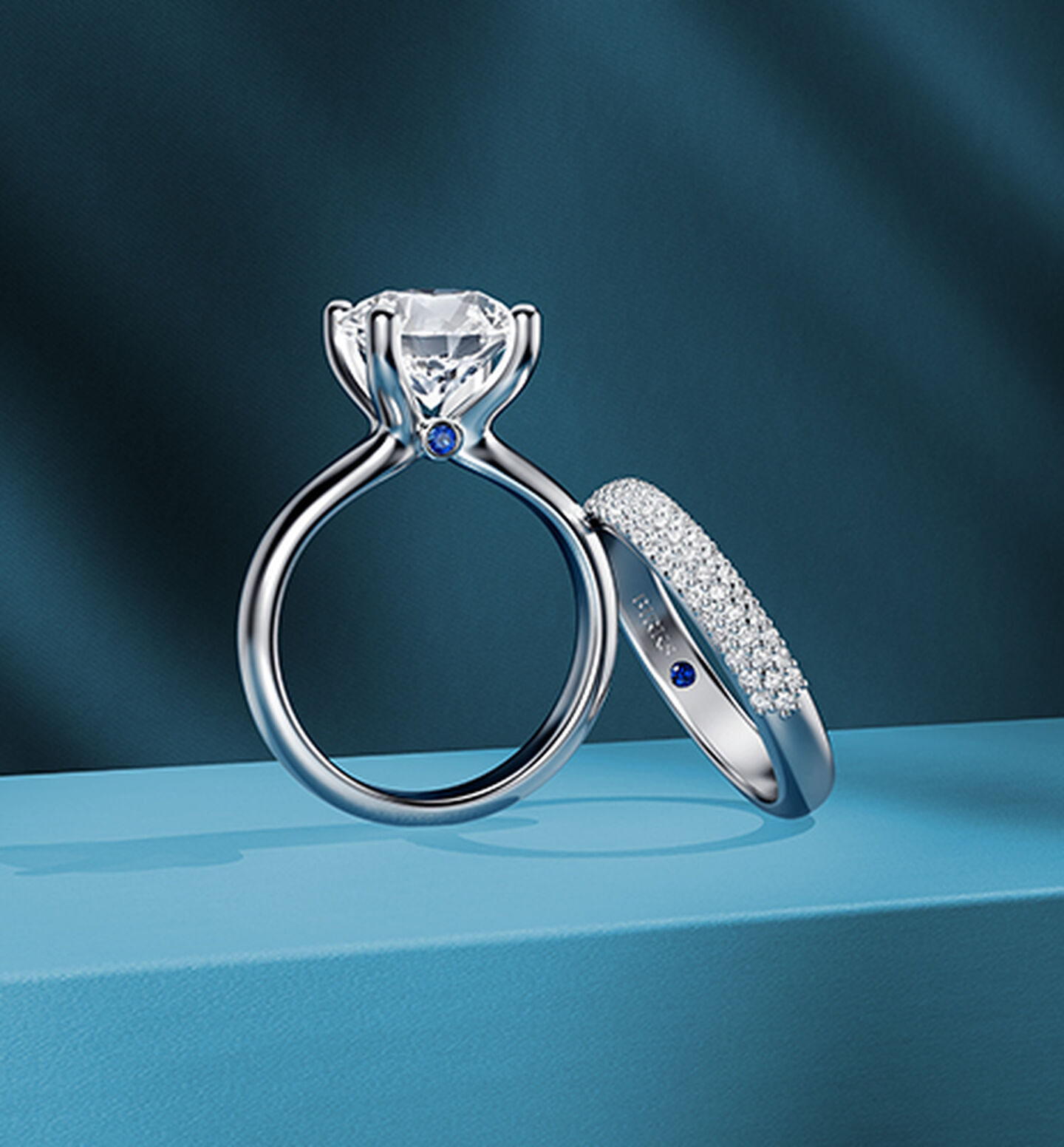 A Birks Blue Sapphire Engagement Ring and wedding band on a blue background.