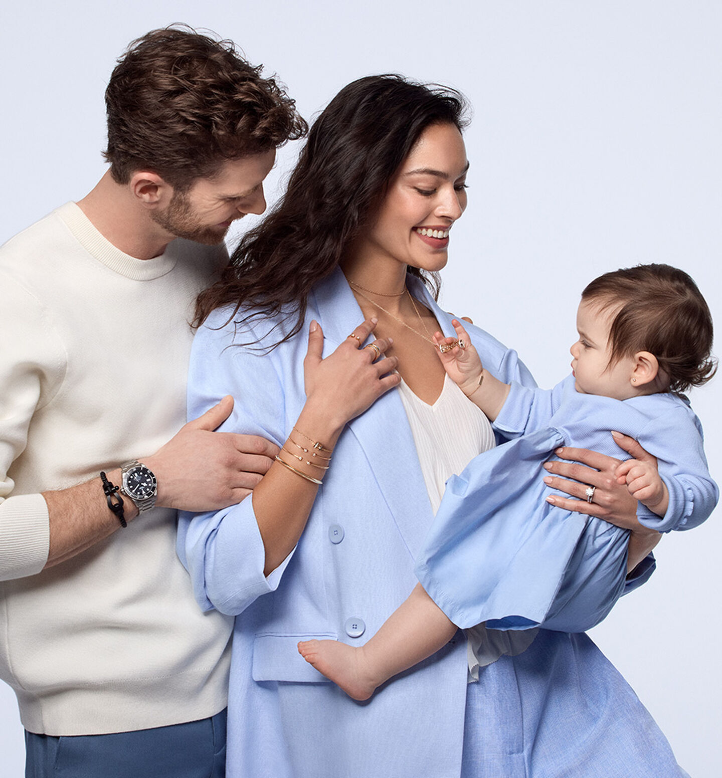 A couple wearing jewellery and watches from Maison Birks holding a child.