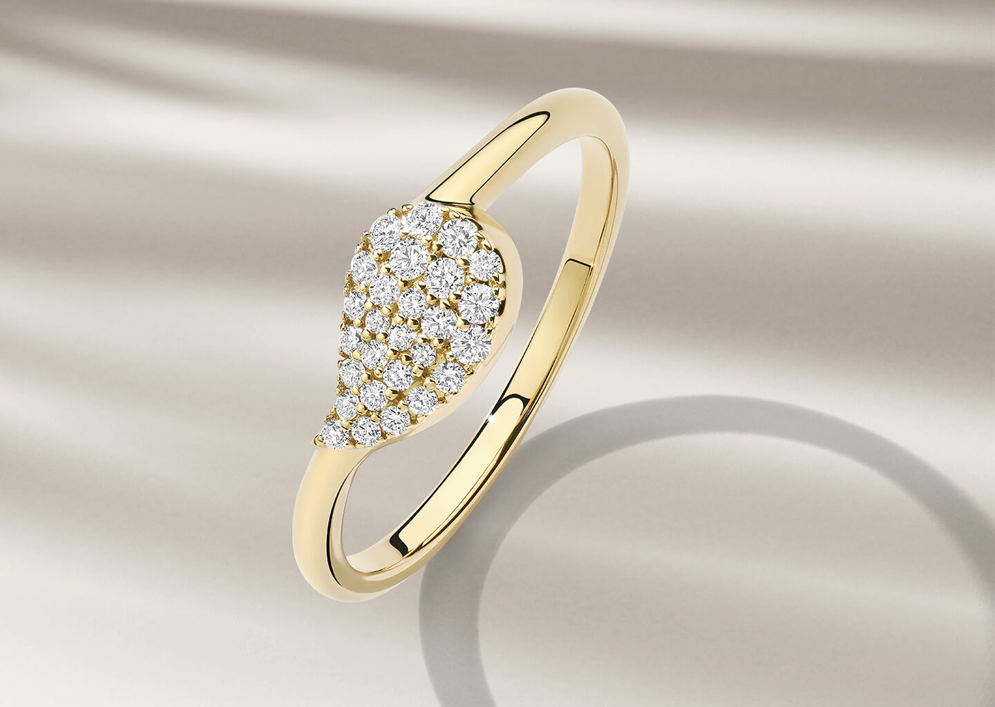 Birks Petale yellow gold and diamond ring on a beige background.