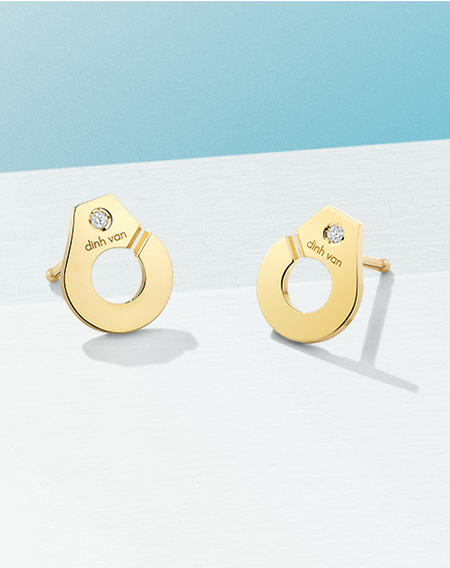 Yellow gold earrings from the Menottes collection of dinh van on a blueish background.