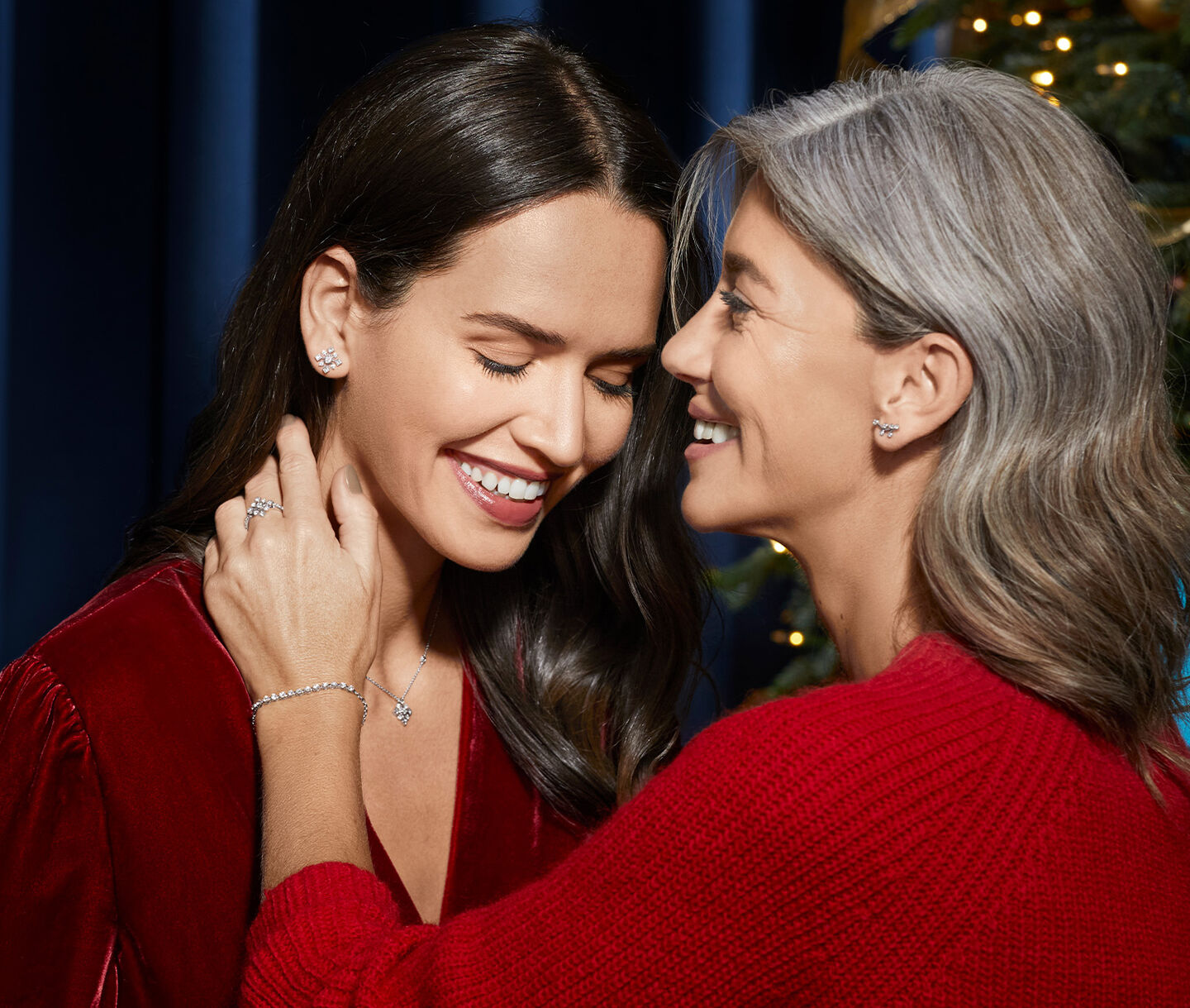 A mother and daughter embrace wearing matching snowflake jewellery.