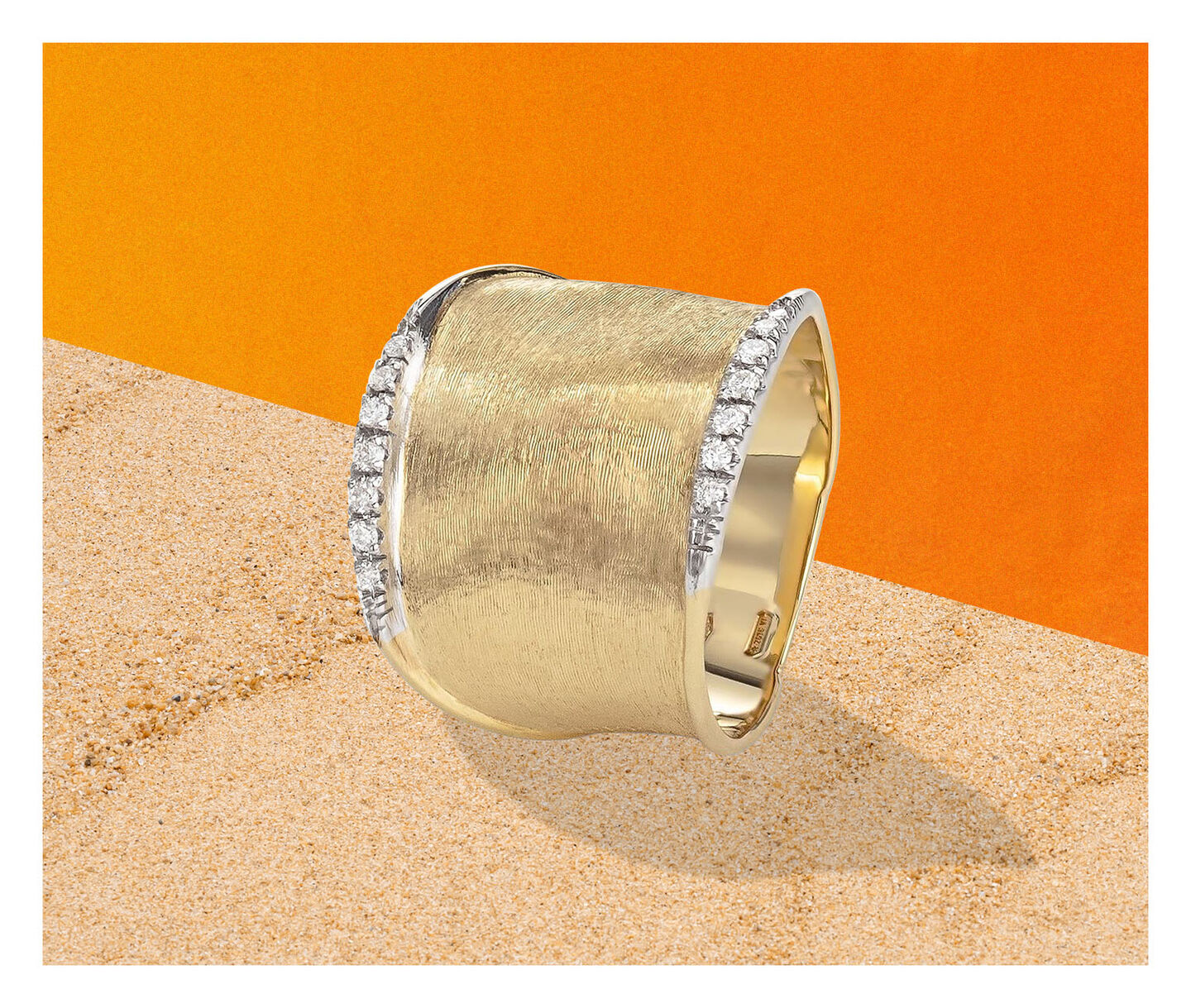 A Marco Bicego Lunaria ring in yellow gold and diamond on a sandy background.