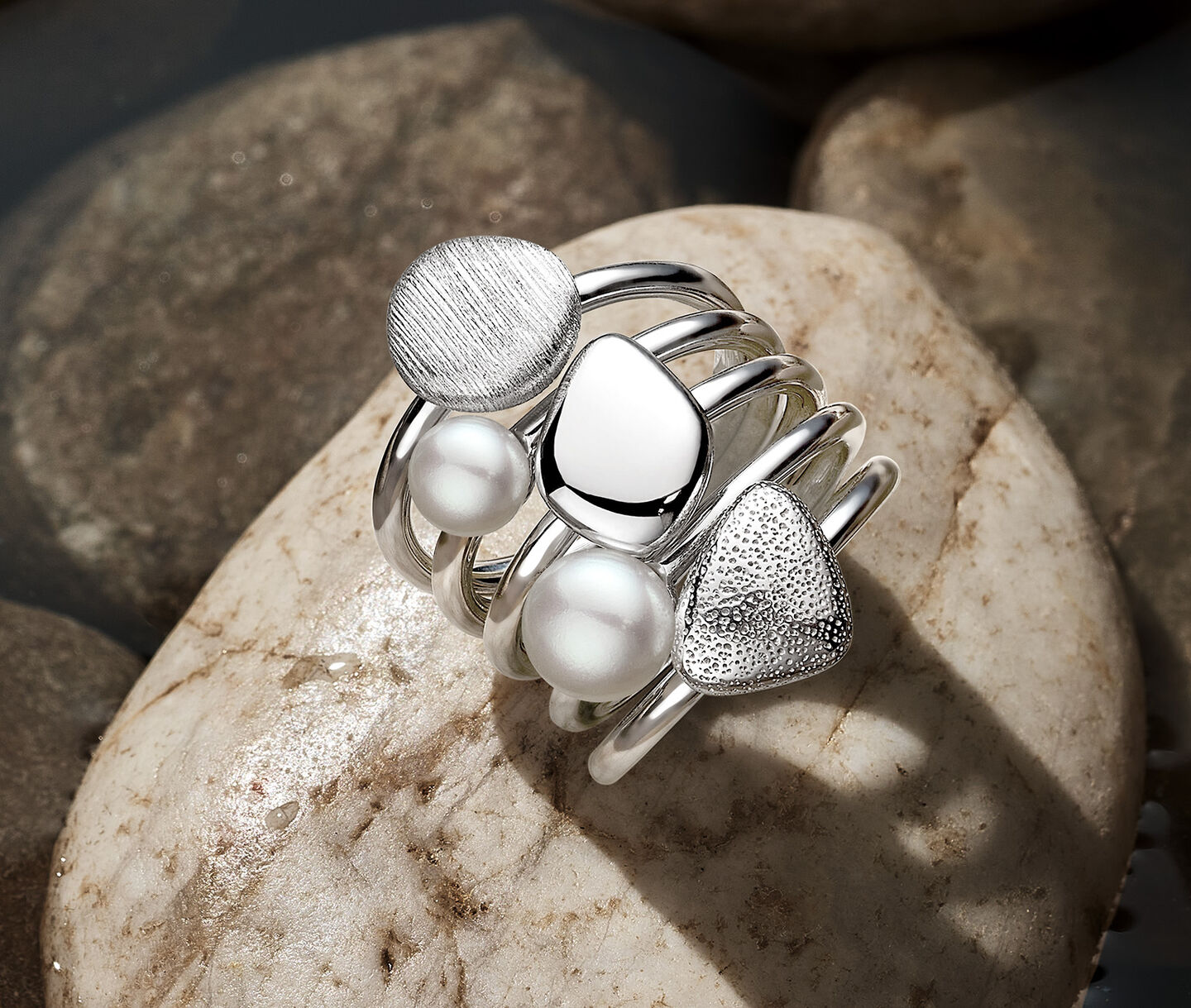 Birks Pebble silver and pearl 5-ring stackable set on rock.