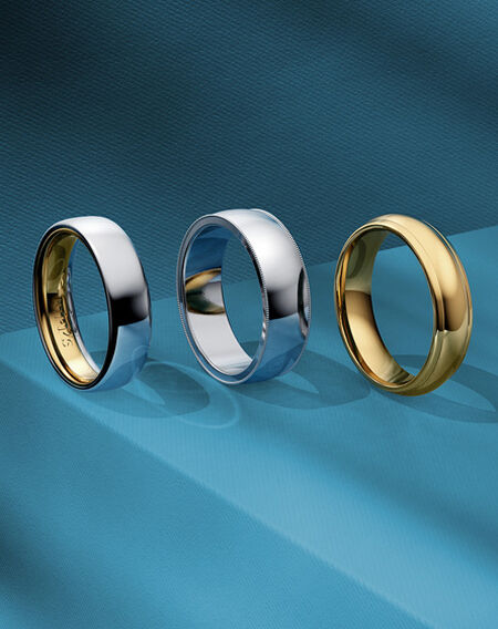 An assortment of wedding bands from Birks on a blue background.