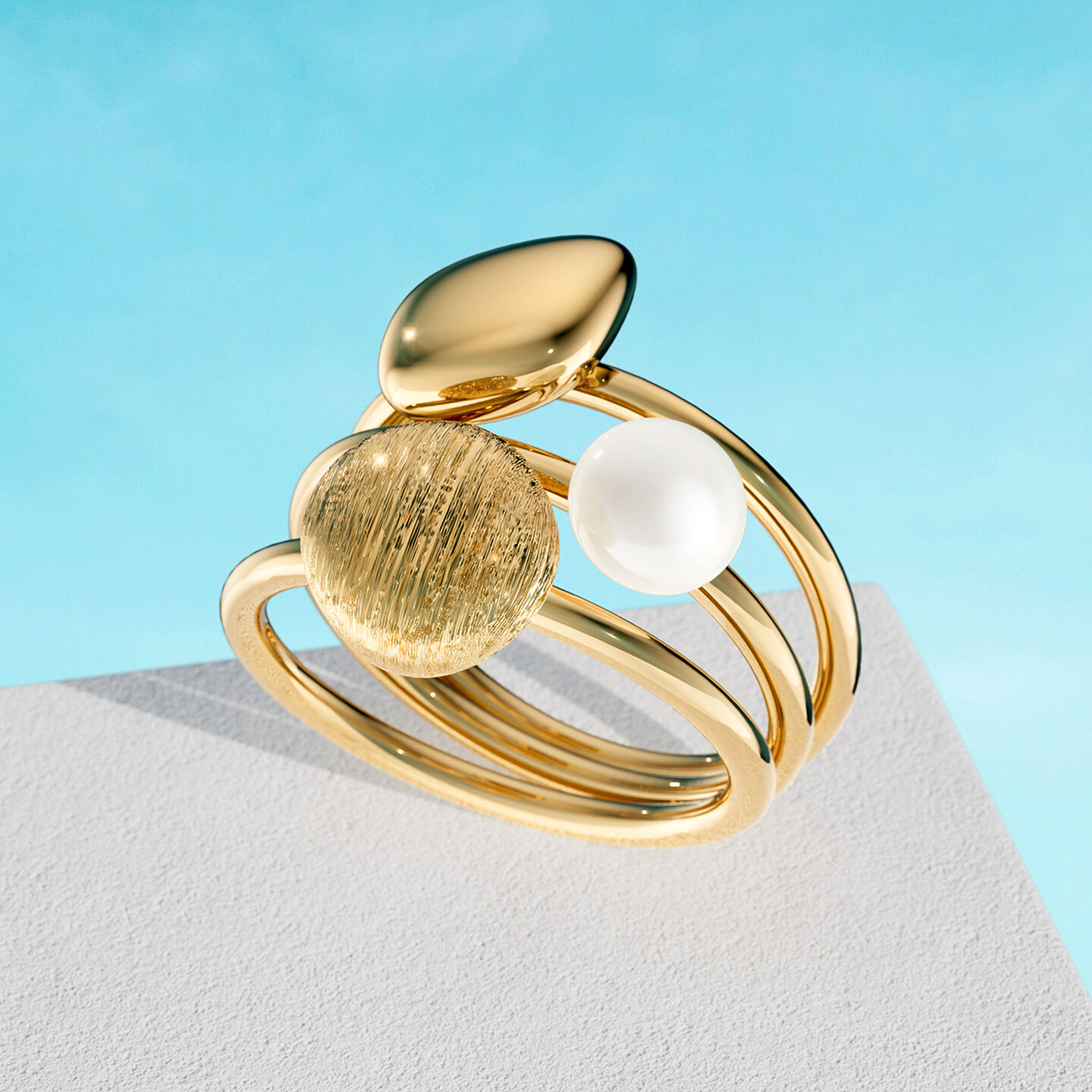 Bague Birks Pebble en or jaune sur un fond bleu.