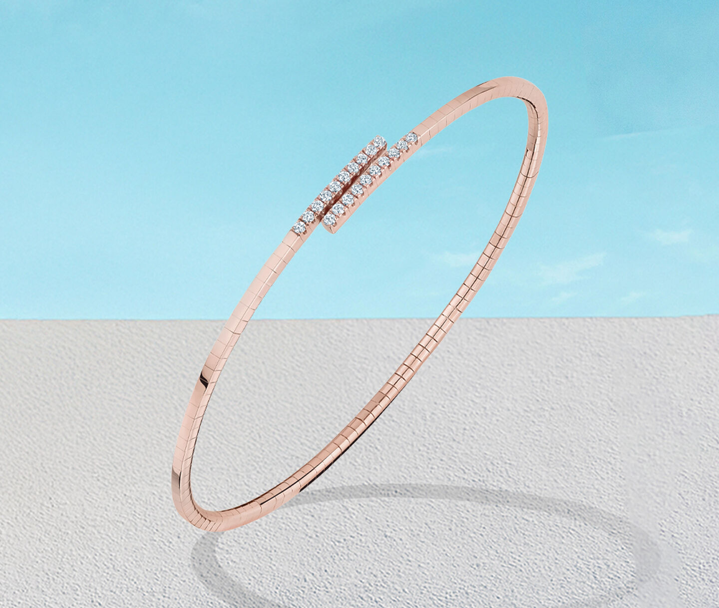 Birks Rosee du Matin diamond and rose gold bracelet on a blue background.