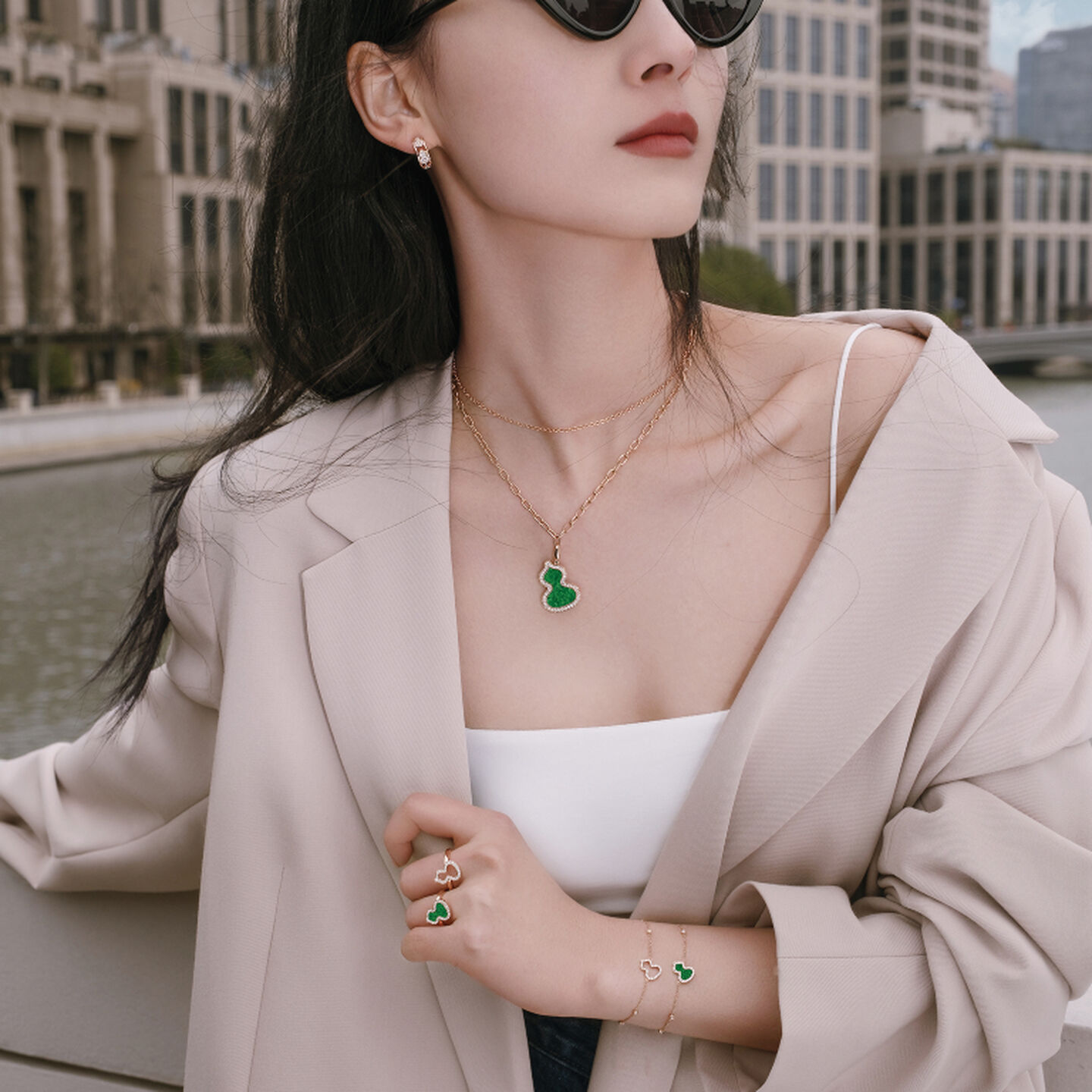 A woman wearing a Qeelin Wulu gold and jade pendant in the city.