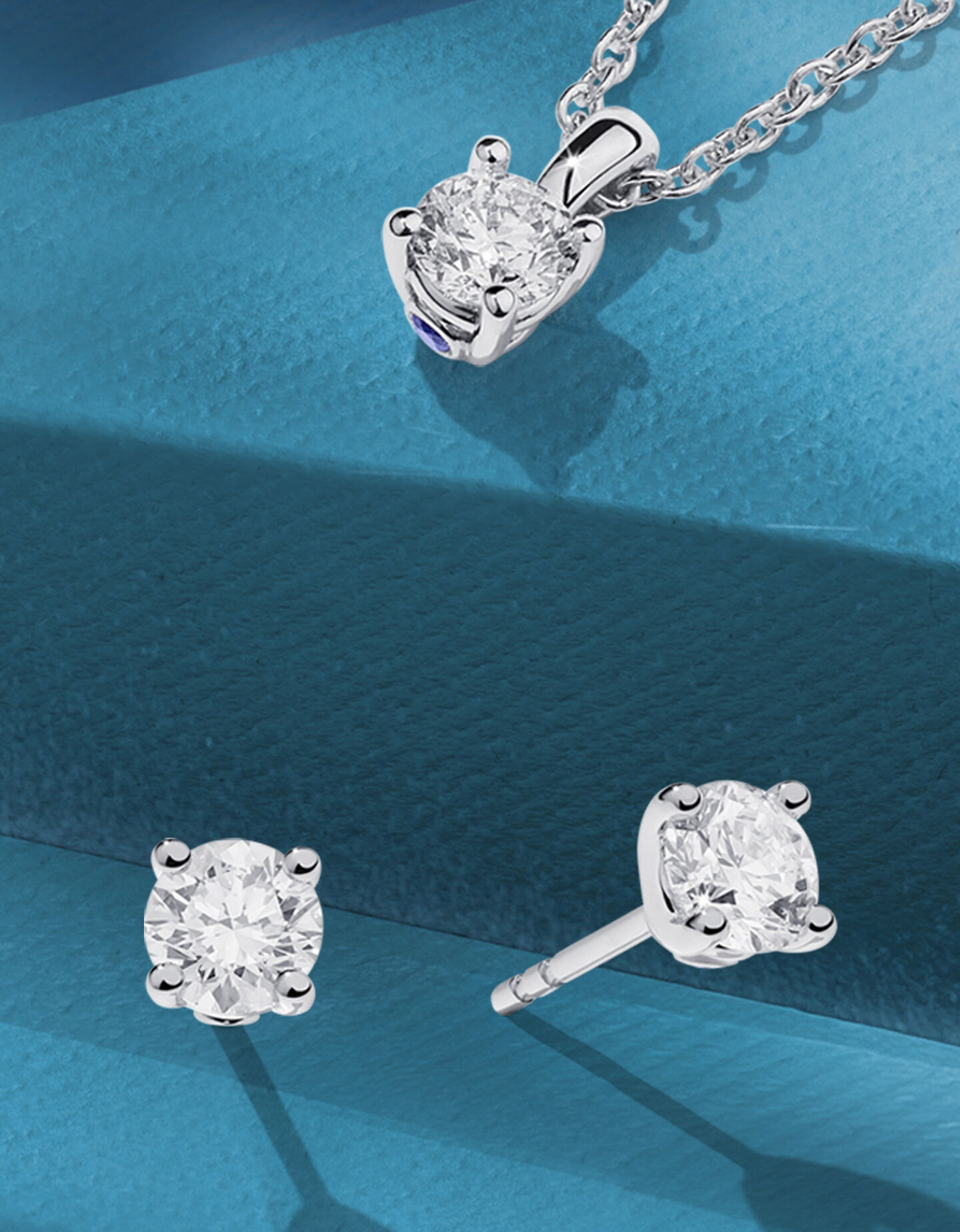 Birks diamond solitaire jewellery on a dark blue background.