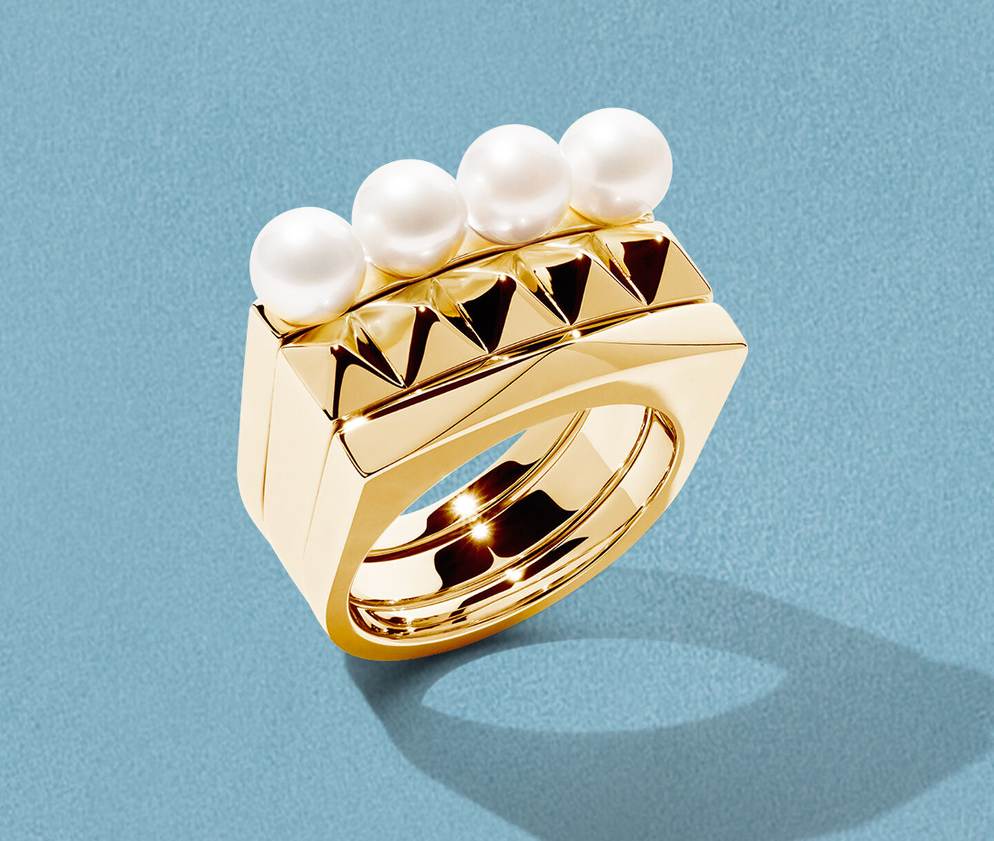 Birks Rock & Pearl gold ring on a blue background.