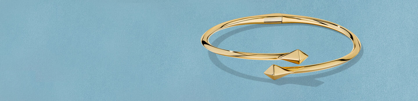 Bracelet en or jaune Birks Rock & Pearl sur un fond bleu.
